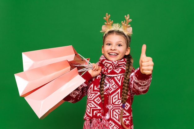 Una ragazza gioiosa con un maglione di Capodanno sta facendo acquisti per le vacanze di Natale nel negozio