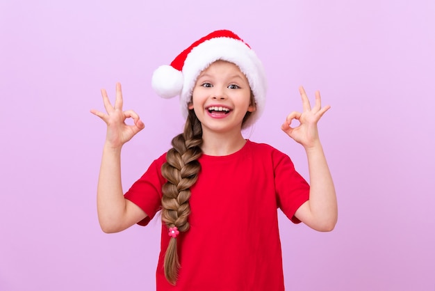 Una ragazza gioiosa in abito di Capodanno mostra un gesto con le mani che tutto va bene.