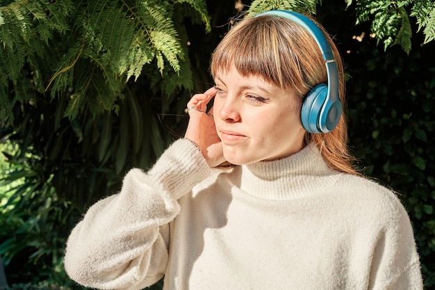 Una Ragazza Giovane Piuttosto Caucasica, Ascolto Di Musica Con Le Cuffie Blu Nel Parco