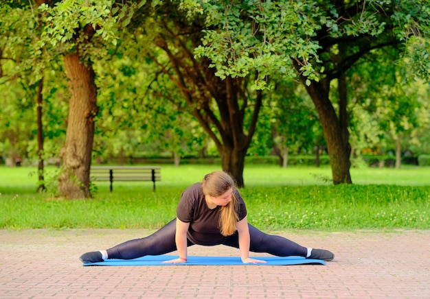 Una ragazza grassoccia fa esercizi di stretching muscolare per essere sana e snella