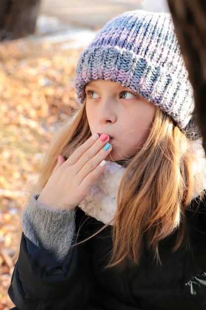 Una ragazza in abiti invernali con una manicure multicolore