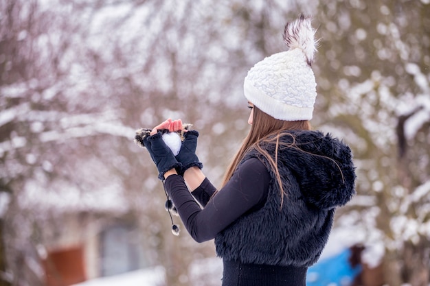 Una ragazza in abiti neri e un cappello bianco lavorato a maglia in inverno