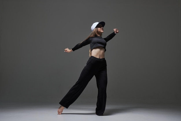 Una ragazza in abiti scuri balla e salta su uno sfondo scuro danza moderna di sfondo