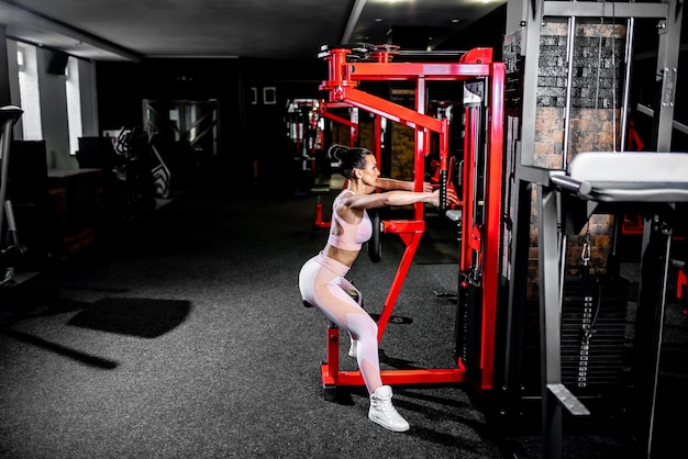 Una ragazza in abiti sportivi in una palestra professionale lavora con attrezzature per il fitness