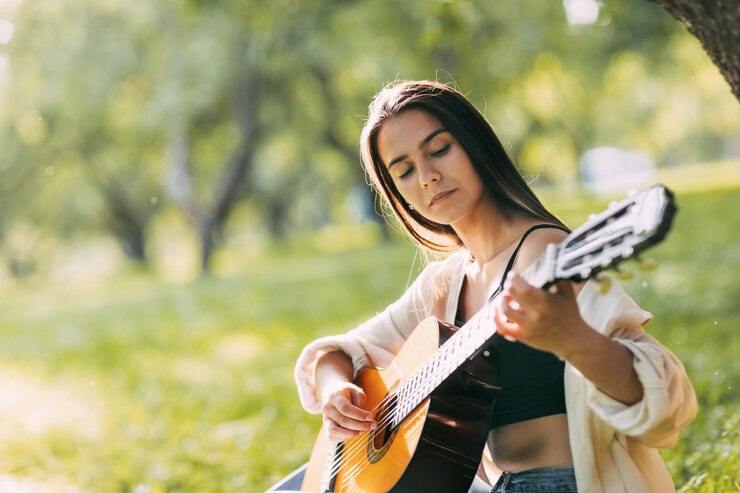 Foto una ragazza in armonia con se stessa suona la chitarra nel parco hobby musicista