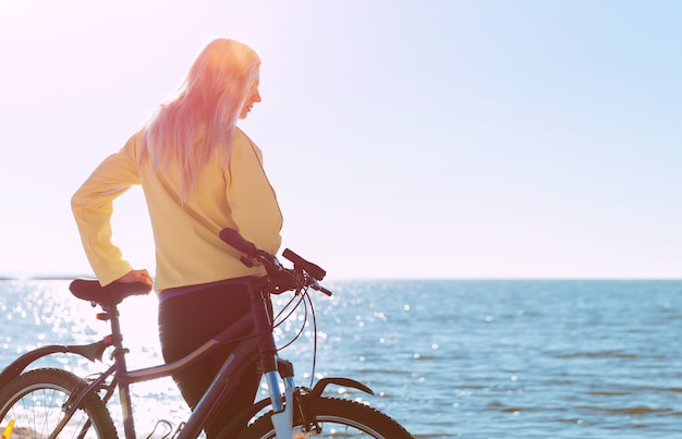 Una ragazza in bicicletta in riva al mare