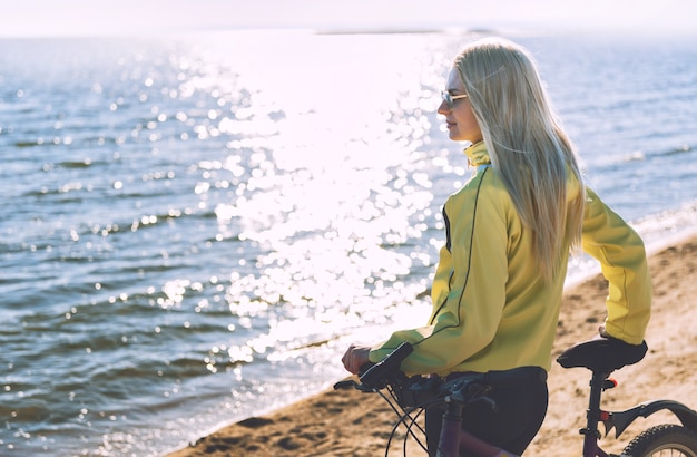 Una ragazza in bicicletta in riva al mare