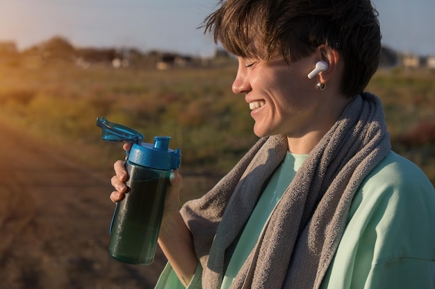 Una ragazza in corsa mattutina. telefono, borraccia, auricolare wireless per sport comodi