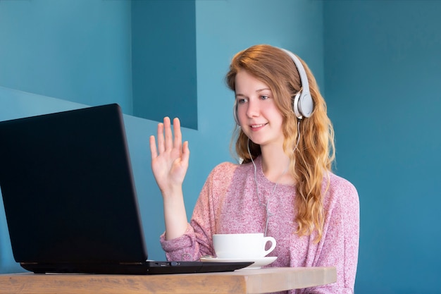 Una ragazza in cuffia comunica tramite chat video su un laptop