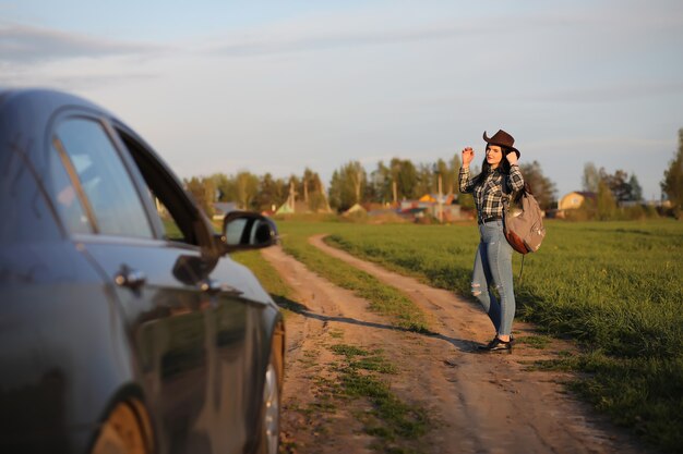 Una ragazza in jeans e cappello viaggia l'estate in campagna