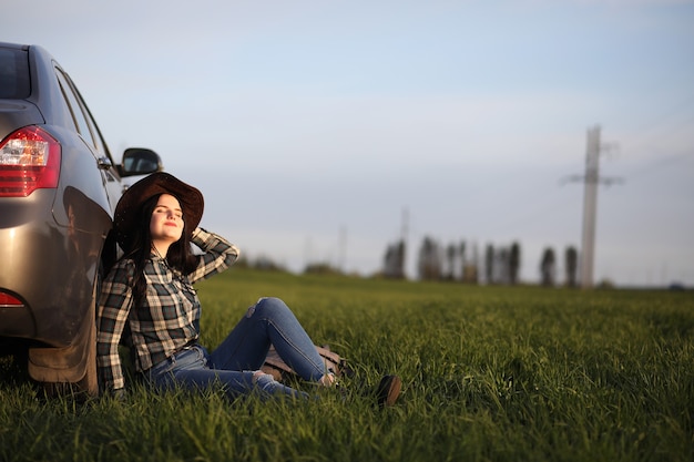 Una ragazza in jeans e cappello viaggia l'estate in campagna