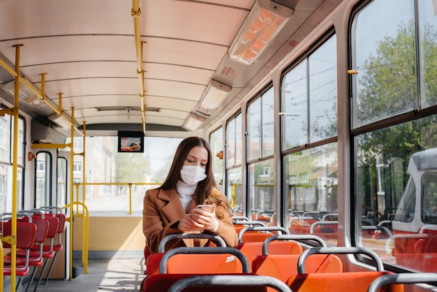 Una ragazza in maschera usa i mezzi pubblici da sola, durante una pandemia. Protezione e prevenzione covid 19.