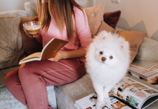 Una ragazza in pigiama a casa legge un libro con il suo cane