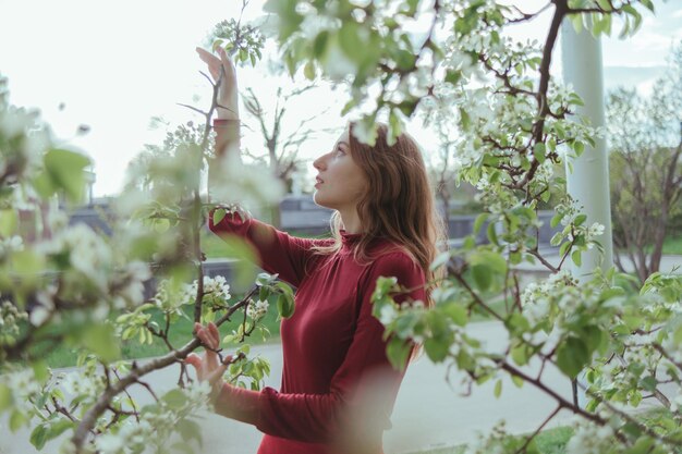 Una ragazza in rosso che ammira i fiori di ciliegio nella soleggiata giornata primaverile del giardino