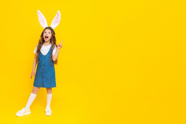 Una ragazza in un abito blu con orecchie da coniglio su uno sfondo giallo