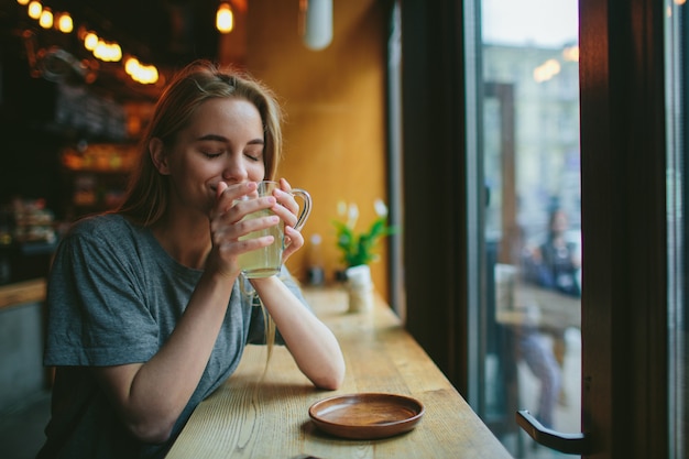 Una ragazza in un bar sta bevendo il tè. Lei è felice