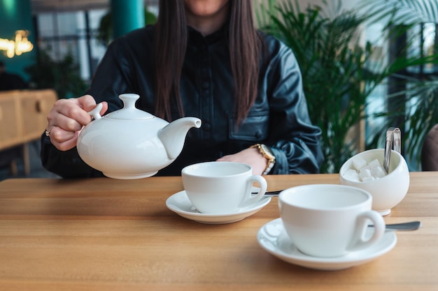 Una ragazza in un caffè versa il tè nelle tazze Bella foto accogliente