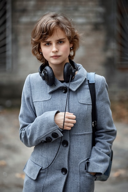 Una ragazza in un cappotto grigio e cuffie