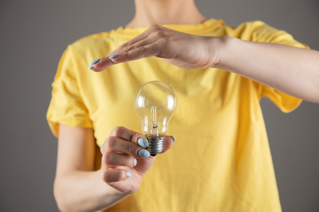 Una ragazza in un vestito giallo che tiene una lampadina