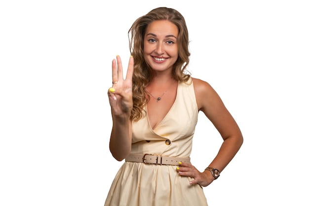 Una ragazza in un vestito in studio. Bel sorriso e segno di vittoria