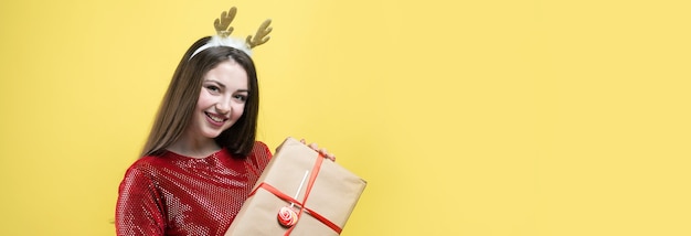 Una ragazza in un vestito rosso con un regalo su uno sfondo giallo