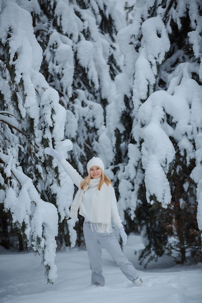 Una ragazza in una foresta d'inverno, bionda, una divertente passeggiata nella natura