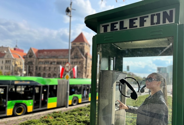 Una ragazza in una moderna cabina telefonica nella piazza della città