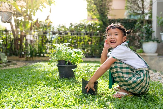 Una ragazza in uniforme scolastica sta piantando una pianta in un giardino.