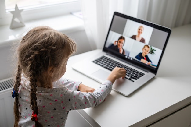 Una ragazza in videoconferenza con una felice insegnante sul computer portatile