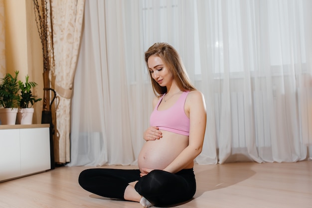 Una ragazza incinta fa yoga a casa. Salute.