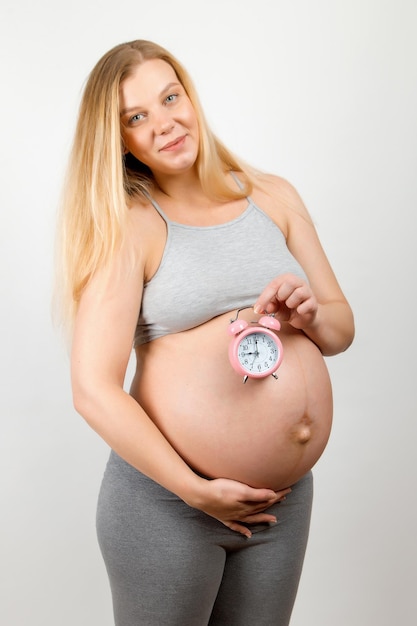 Una ragazza incinta tiene in mano un orologio Un simbolo dell'attesa del parto un viaggio all'ospedale di maternità