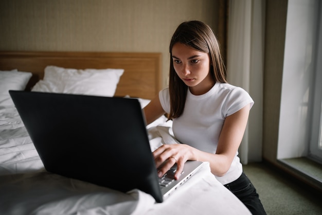 Una ragazza lavora sul letto in un laptop