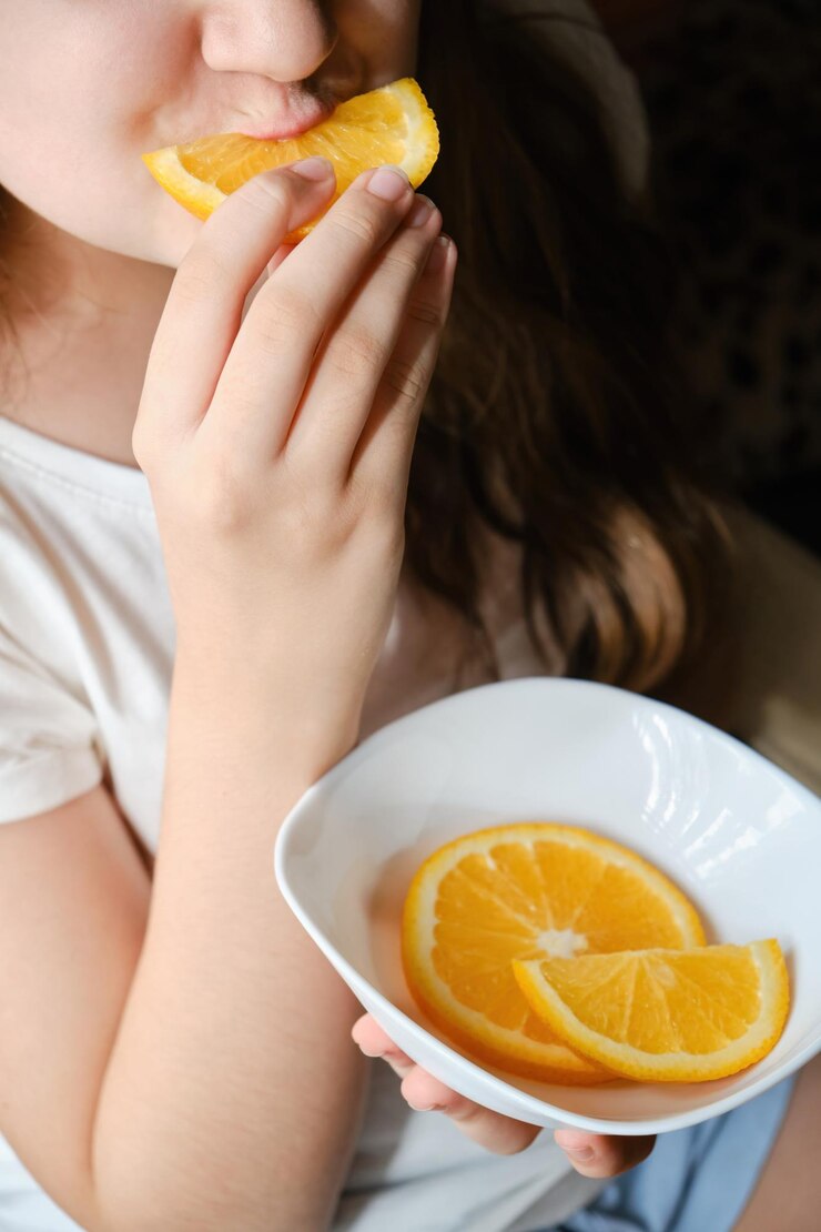 Una ragazza mangia una fetta d'arancia da vicino senza occhi Vitamina nutrizione frutta