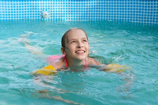 Una ragazza nuota felicemente in piscina in estate