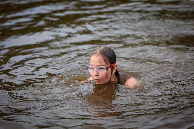 Una ragazza nuota nel fiume in una calda giornata estiva