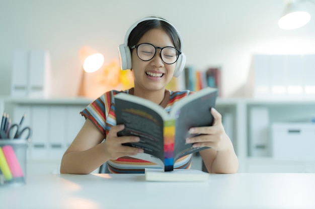 Una ragazza o una studentessa กำลงอานหนงสอ in biblioteca mentre indossa gli occhiali Sorride e sembra felice