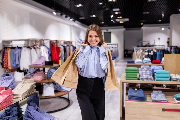 Una ragazza positiva con un bel sorriso in un vestito chic compra elegante