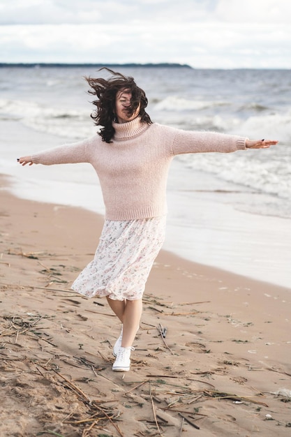 Una ragazza romantica gode del vento dalla danza del mare di un uomo felice sull'oceano donna in un abito leggero