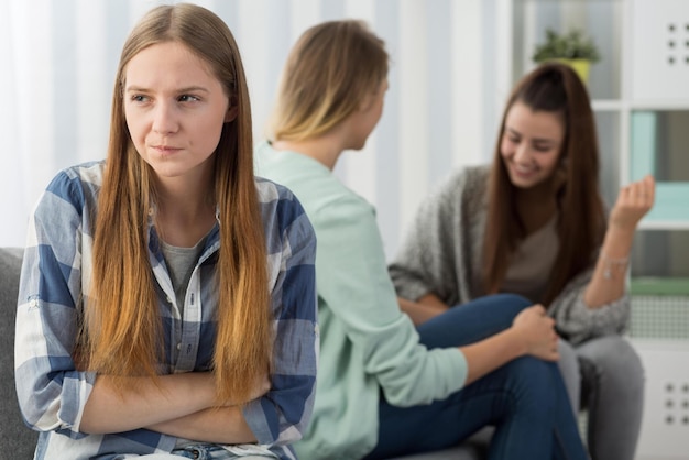 Una ragazza si siede su un divano con i suoi amici sullo sfondo