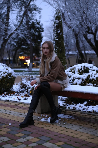 una ragazza si siede su una panchina nella neve