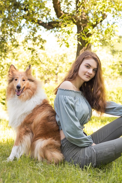 Una ragazza si siede sull'erba accanto al suo cane