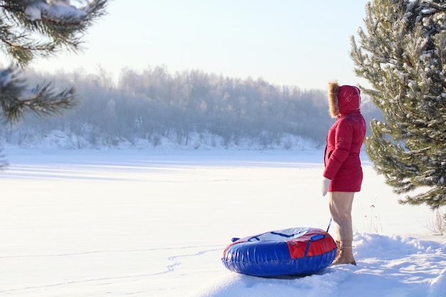 Una ragazza si trova su uno scivolo con un tubo gonfiabile invernale rosso e blu per sciare uno stile di vita attivo