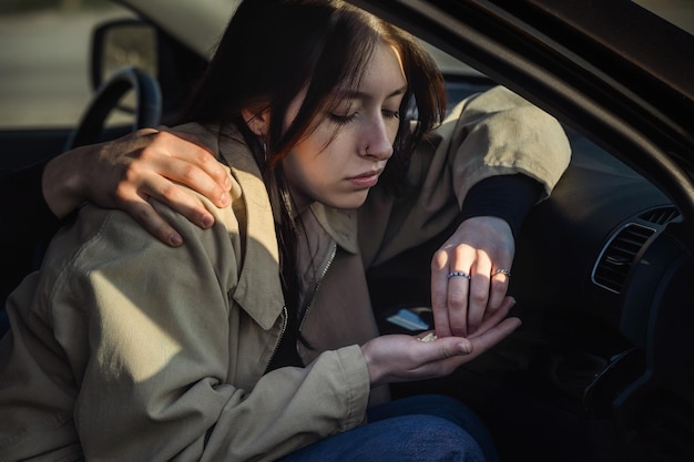 una ragazza siede in macchina in mano ha una manciata di pillole psicotrope