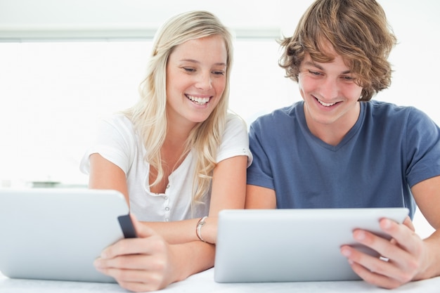 Una ragazza sorridente guarda nel tablet dei suoi fidanzati