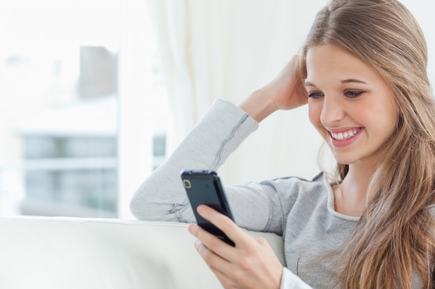 Una ragazza sorridente guardando il suo telefono cellulare