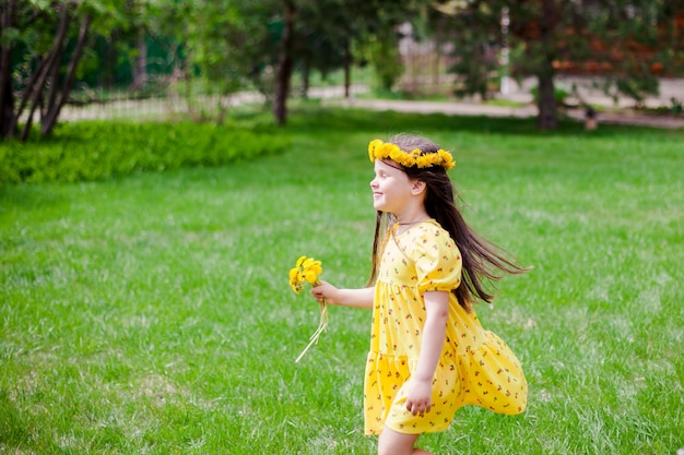 Una ragazza sorridente in un vestito giallo e fiori gialli con gli occhi chiusi gode di una calda giornata di sole in ...