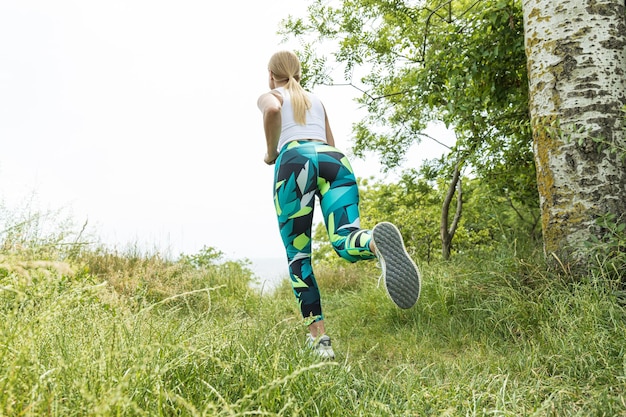 Una ragazza sportiva con le cuffie sta facendo jogging in natura