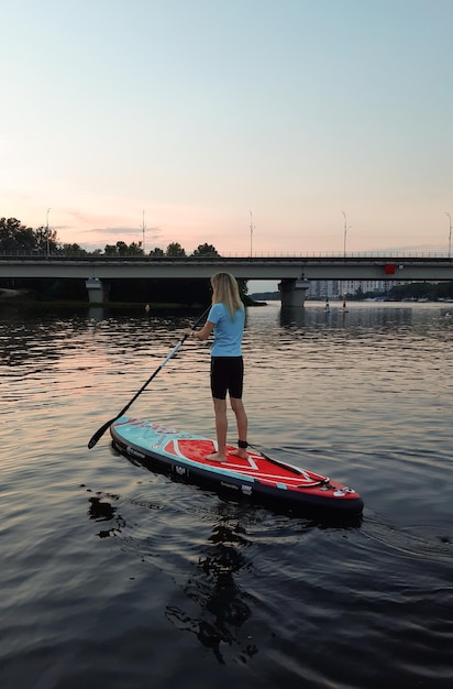 Una ragazza sportiva nuota su una tavola da paddle stand-up e si aiuta con una pagaia