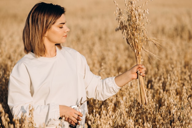 Una ragazza sta tenendo un mazzo di orecchie di avena.