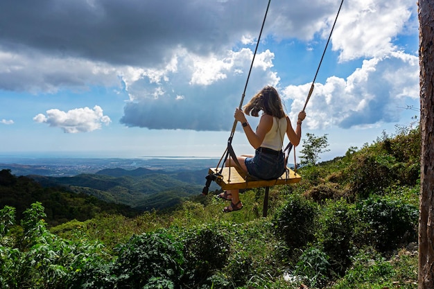 Una ragazza su un'altalena con vista sulle montagne